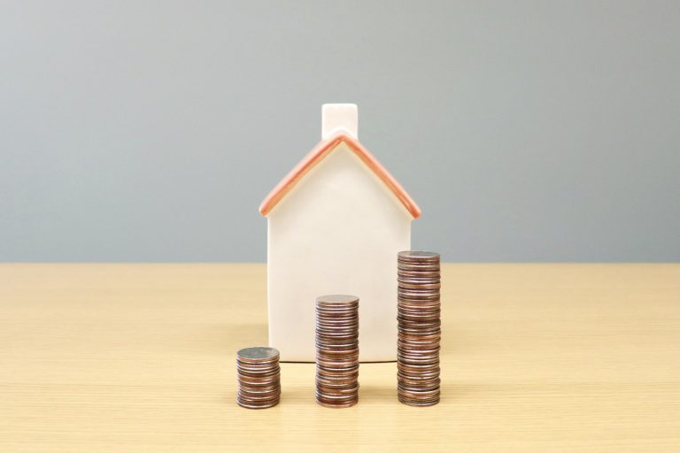 A model house beside stacks of coins
