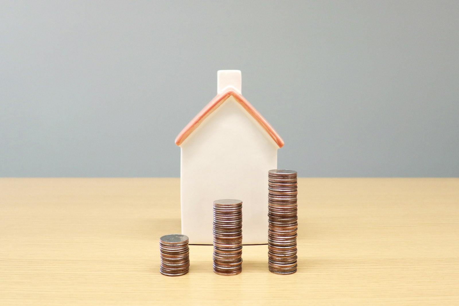 A model house beside stacks of coins