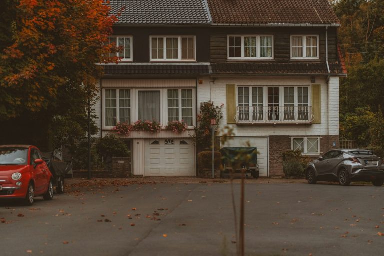 A detached house with cars parked outside in autumn
