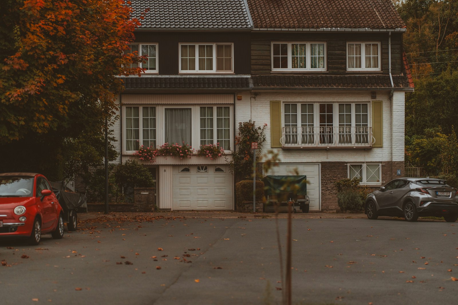 A detached house with cars parked outside in autumn