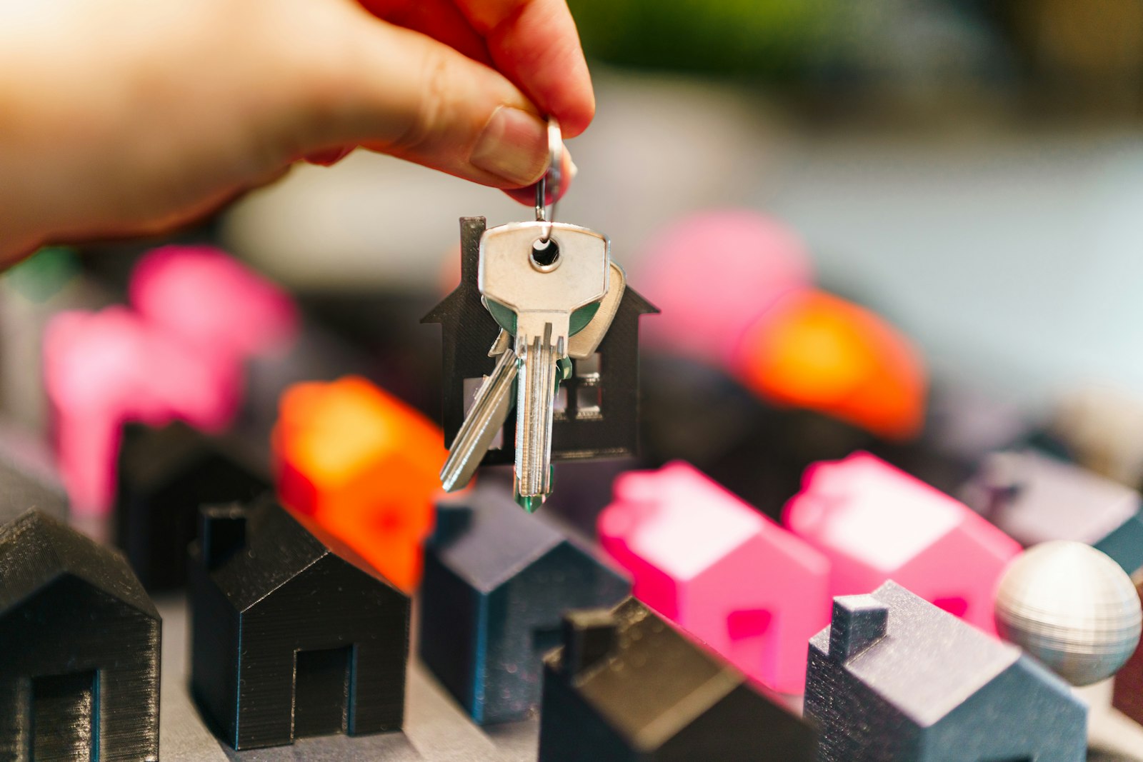 A hand holding house keys over model houses